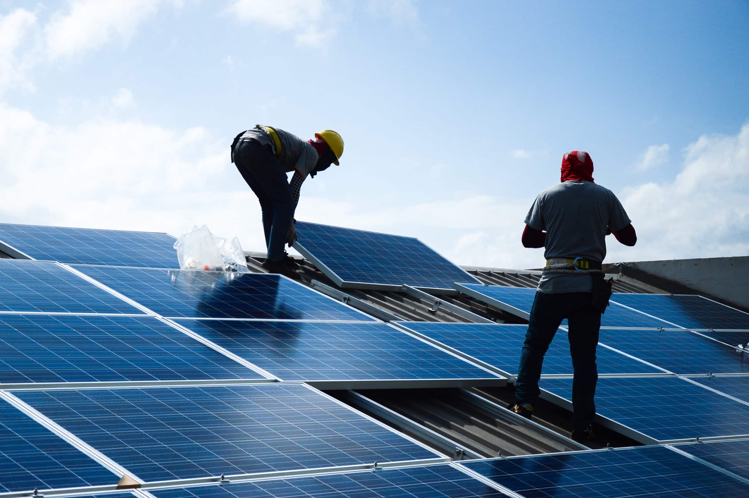 2 ouvriers posent des panneaux solaires sur un toit