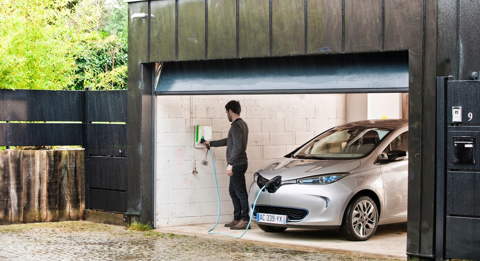 homme rechargeant une voiture électrique dans son garage