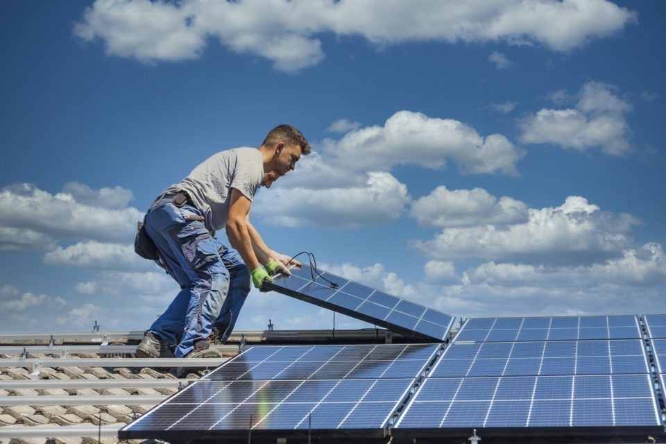 professionnels installant un panneau solaire sur un toit