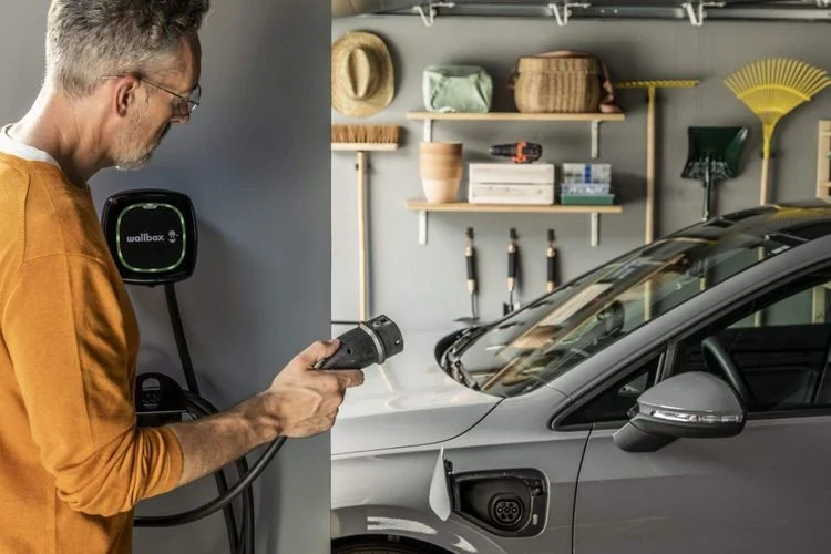 homme tenant le cable de recharge pour sa voiture électrique